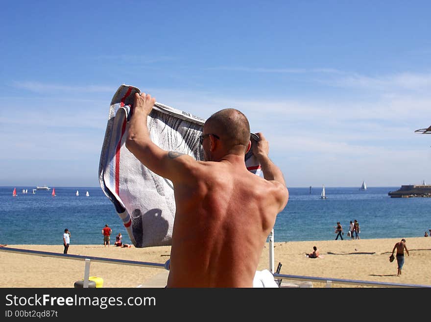 Man taking his towel at the beach at the city of Barcelona, Catalunya, Spain, Europe. Man taking his towel at the beach at the city of Barcelona, Catalunya, Spain, Europe