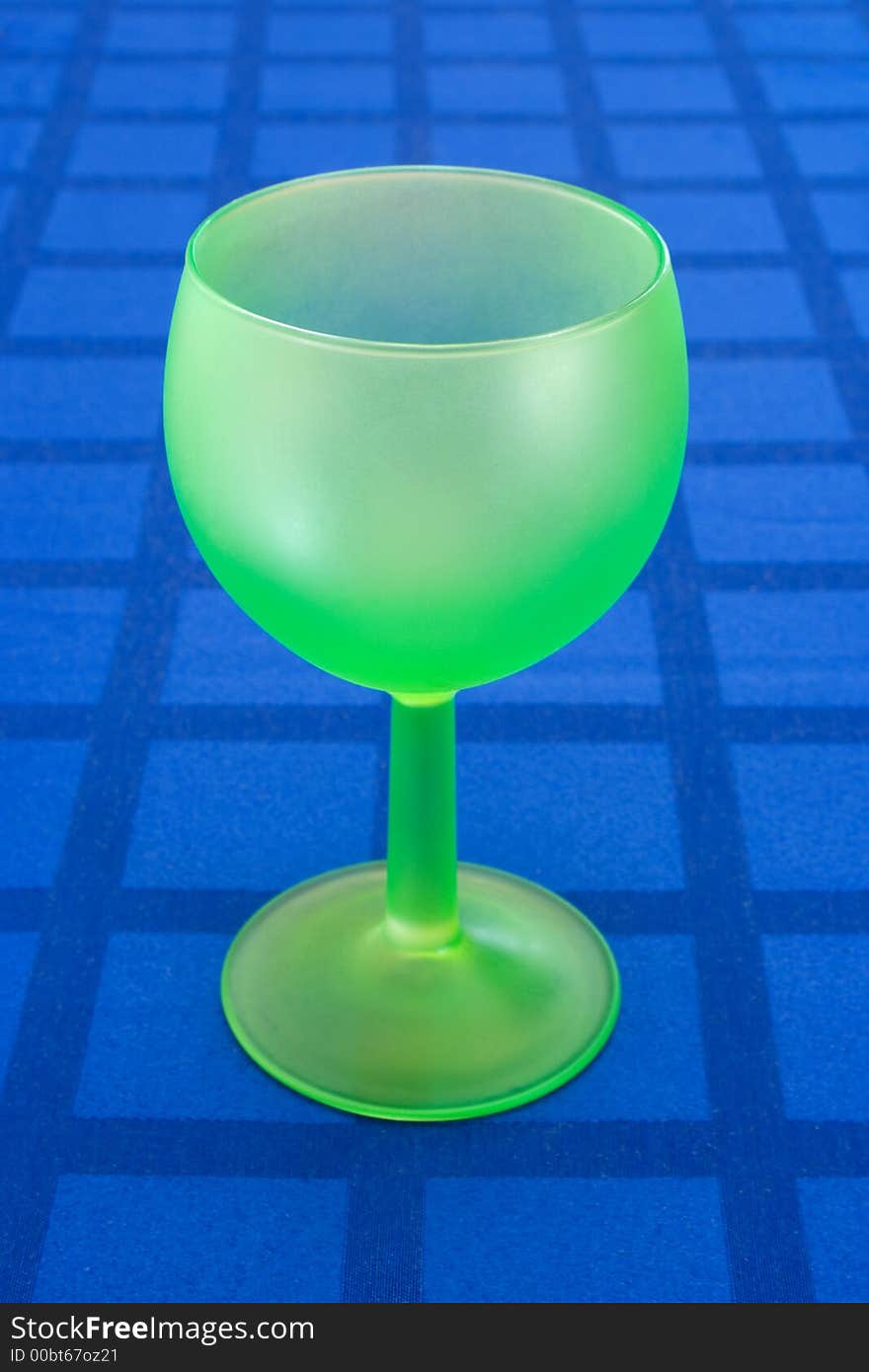 Stylish green wineglass on blue tablecloth