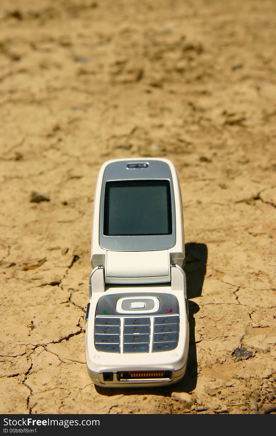 White mobile cell phone in a dry, cracked river bed. White mobile cell phone in a dry, cracked river bed