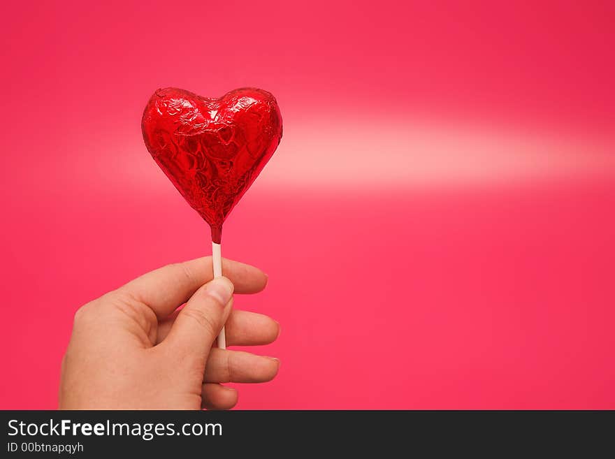 Woman holding a heart lolly in her hand. Woman holding a heart lolly in her hand