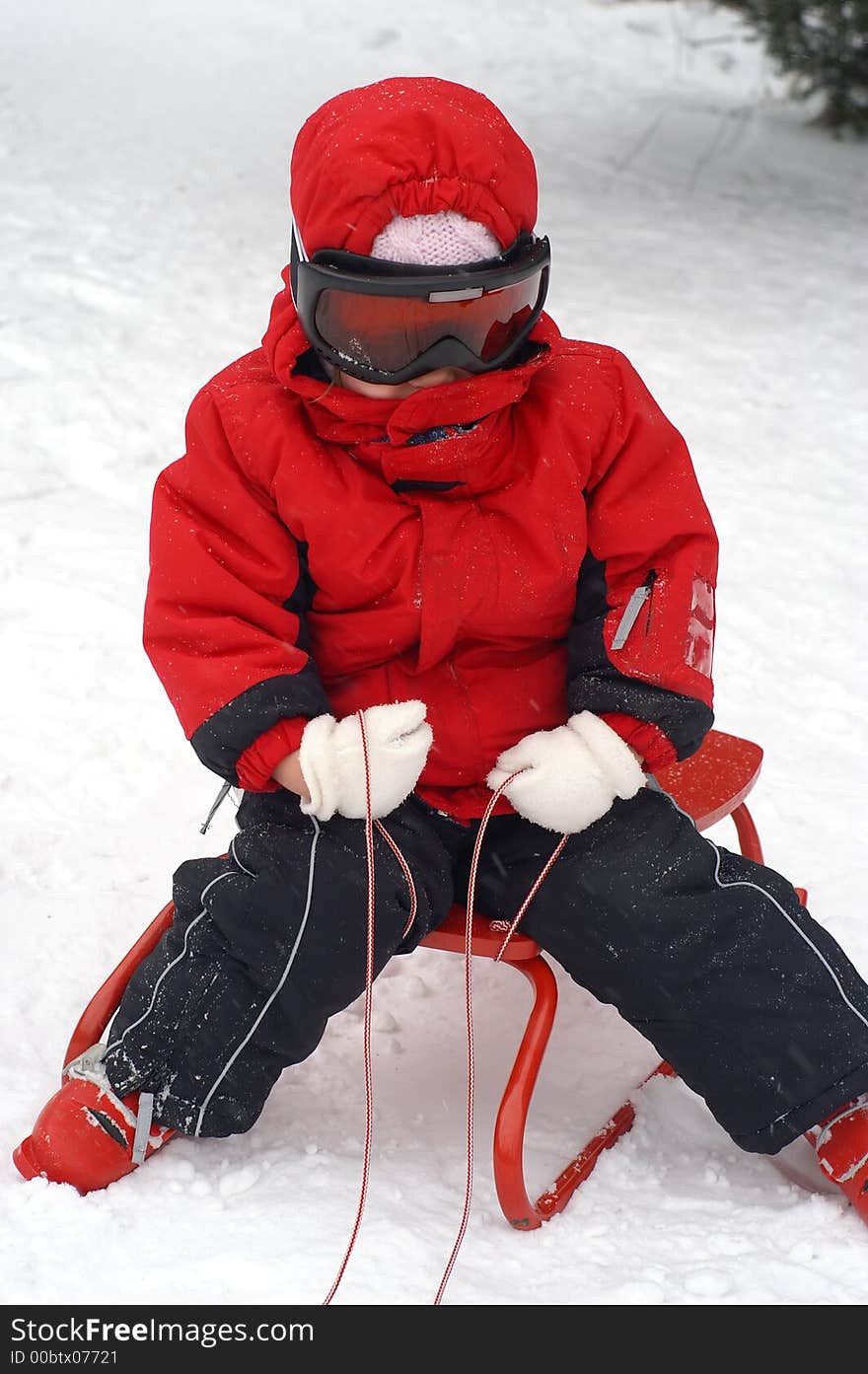 Two and a half year old girl playing with a red sledge. Two and a half year old girl playing with a red sledge.