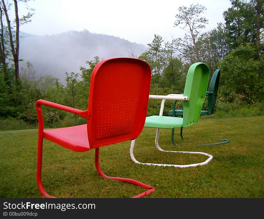 A lovely view of the mountains and fog with colorful chairs in the foreground. A lovely view of the mountains and fog with colorful chairs in the foreground.