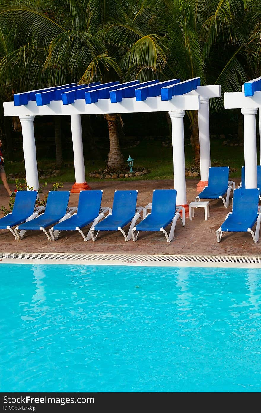 Blue lounge chairs around a tropical blue pool setting. Blue lounge chairs around a tropical blue pool setting