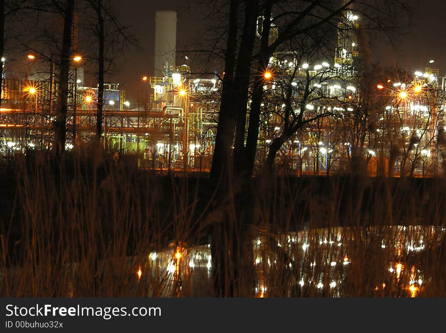 An oil refinery construction and reflection in a river at night. An oil refinery construction and reflection in a river at night