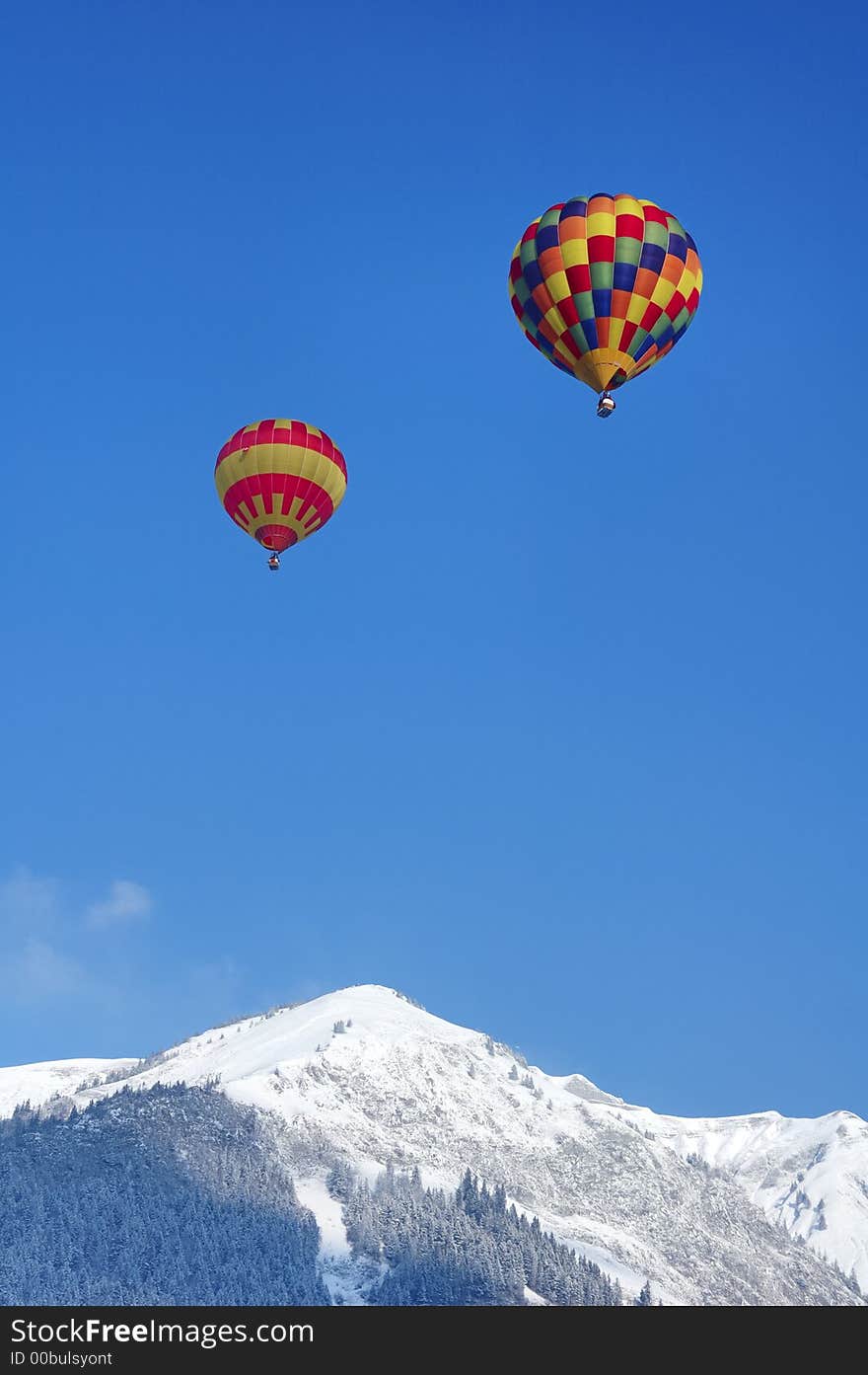 Two hot-air balloons rising over a snowy ridge in Switzerland. Two hot-air balloons rising over a snowy ridge in Switzerland.