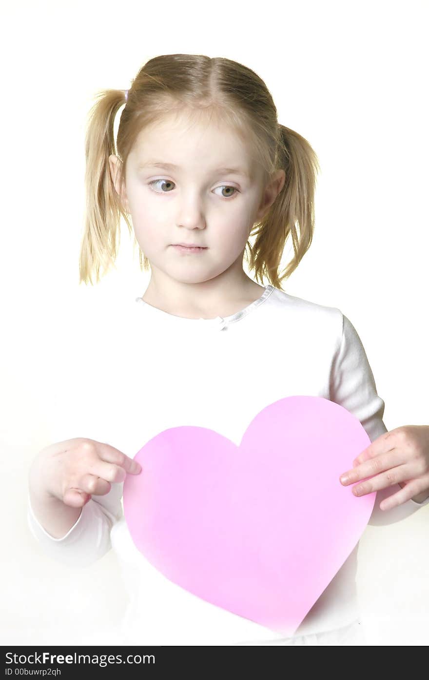 Little girl dressed in white holding a valentine heart. Little girl dressed in white holding a valentine heart