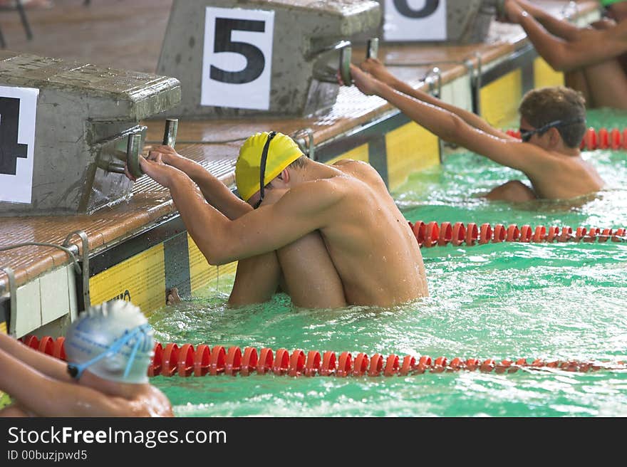 Young men at start of backstroke event hanging on to starting blocks. Young men at start of backstroke event hanging on to starting blocks