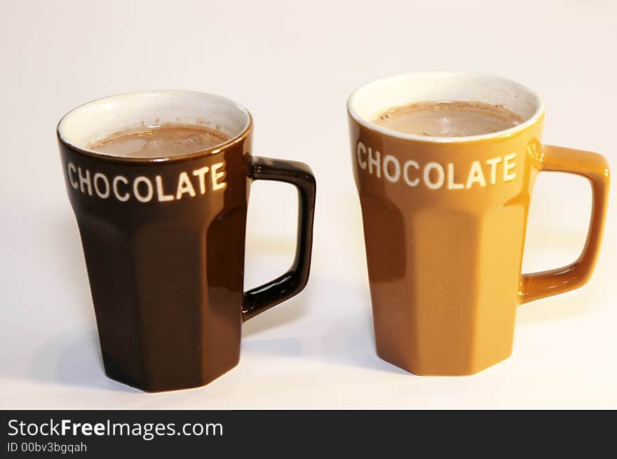 Two cups hot chocolate milk light background