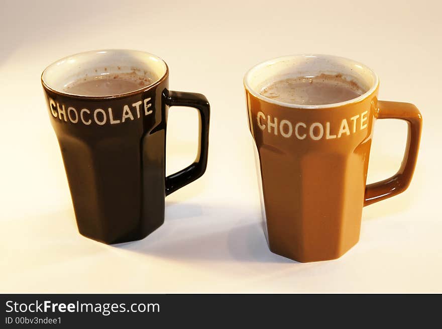 Two cups hot chocolate milk light background