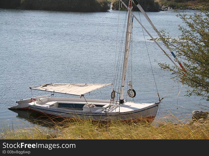 Traditional Egyptian sailing boat known as Felucca anchored at an island in Nile river. Traditional Egyptian sailing boat known as Felucca anchored at an island in Nile river.