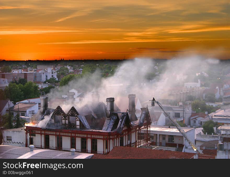 Voluntary fireman attempting to extinguish a FIRE from the top of a ladder. Voluntary fireman attempting to extinguish a FIRE from the top of a ladder