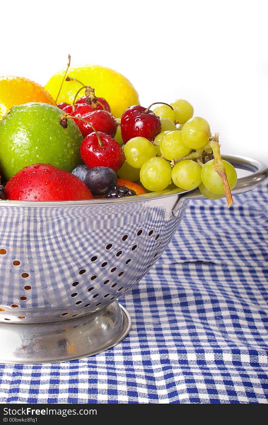 Freshly washed fruits drain in a stainless steel colander.