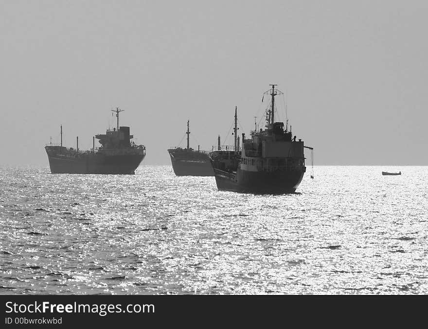 Three small oil tanker at anchor offshore in strong sunlight. Black and white photo.