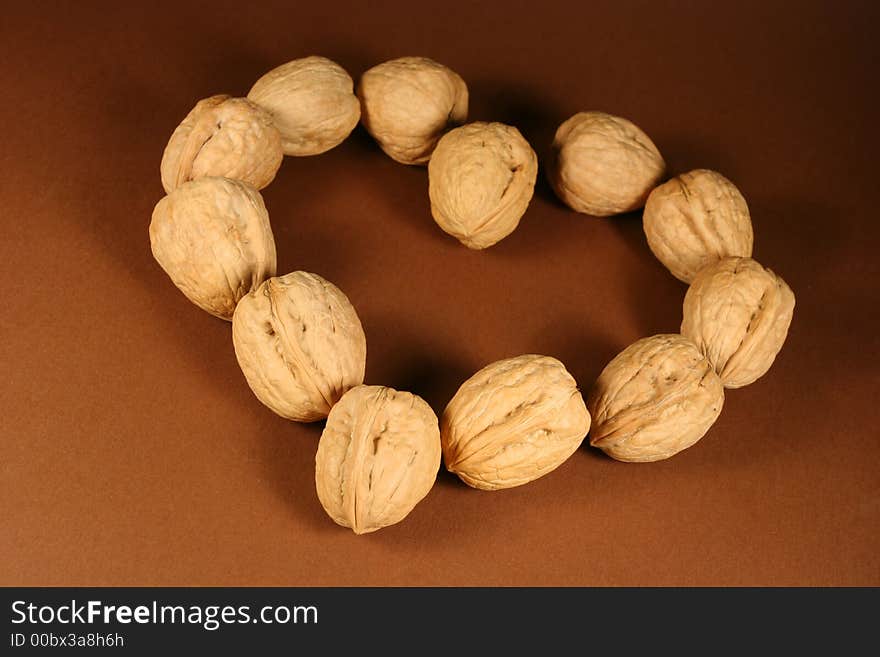 Heart made from walnuts on a brown background.