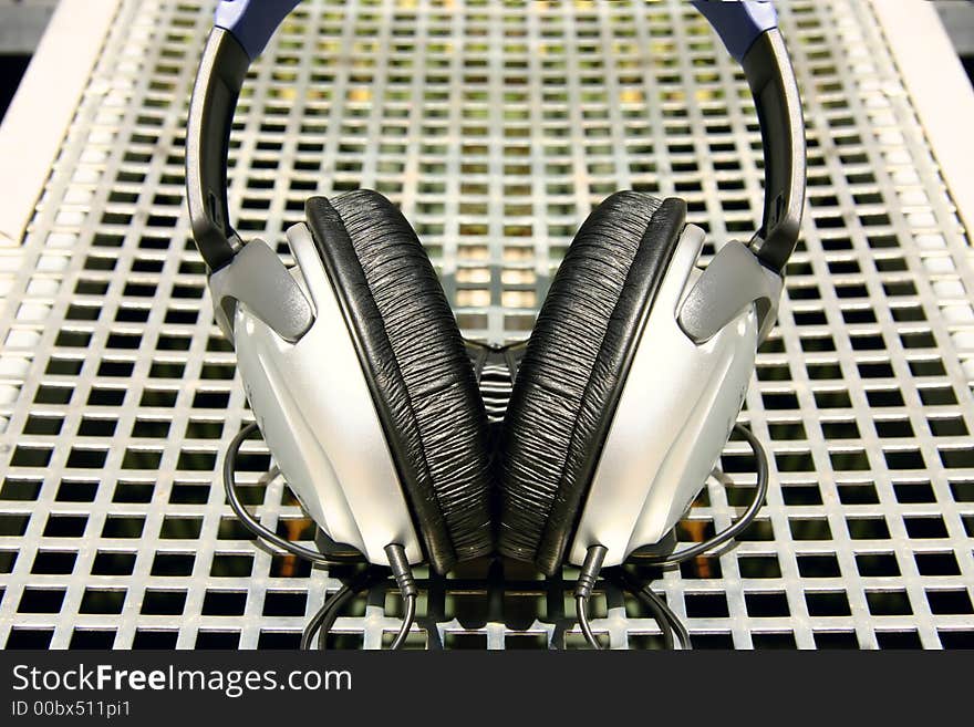 Symmetrical silver and black headphones on silver metal grid background. Symmetrical silver and black headphones on silver metal grid background