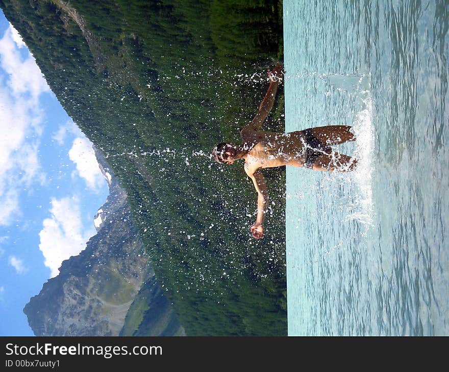 A young man is taking bath in a mountain lake Kucherlinskoe,temperature is 8-9 degrees centigrade. A young man is taking bath in a mountain lake Kucherlinskoe,temperature is 8-9 degrees centigrade