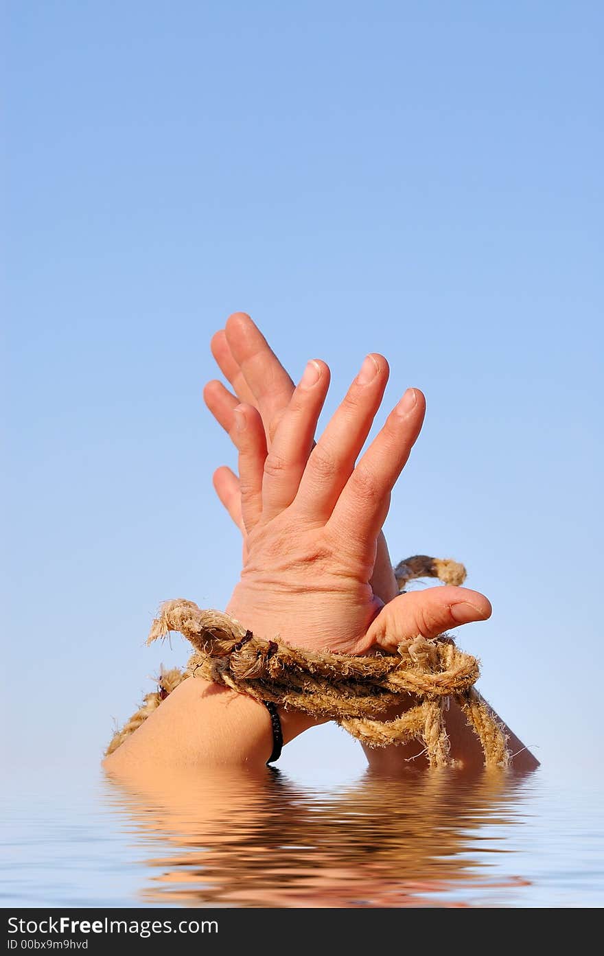 Close up of female hands tied in a rope on the sea (concept for slave or cast-away theme)