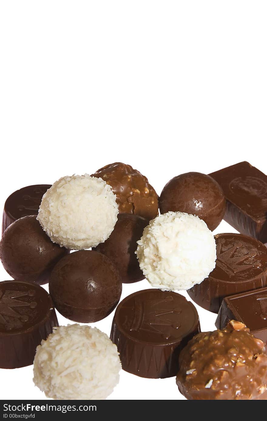 Appetizing chocolate candies with a nut and coconut are sparse on a white background