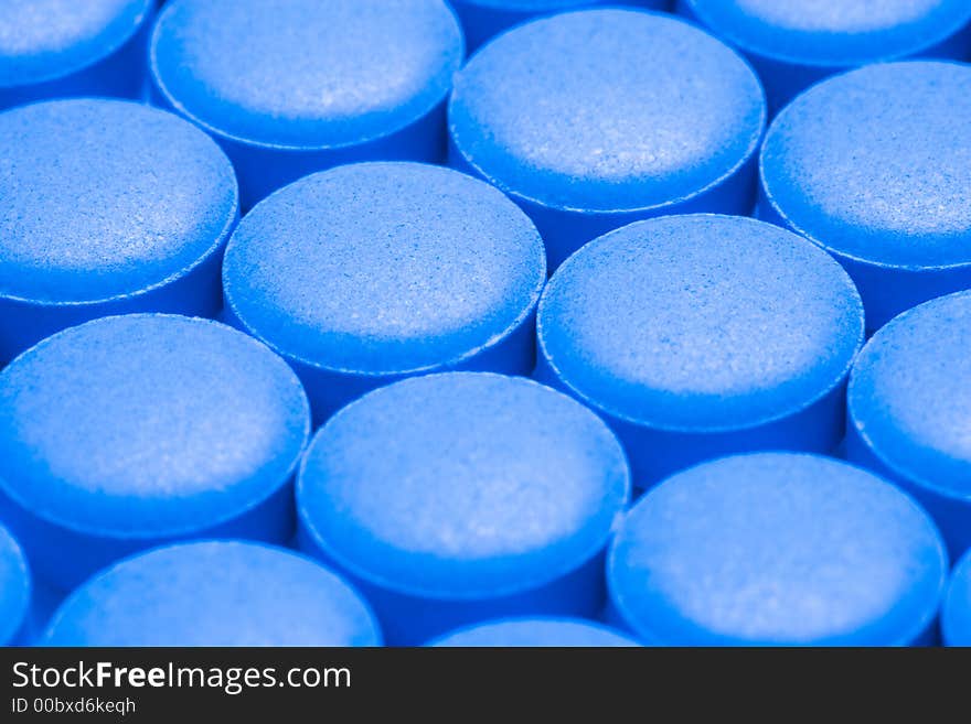 Round blue pills sit on a table.