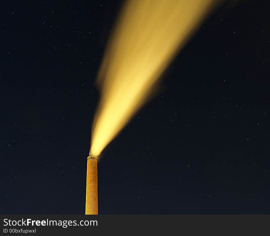 A brick chimney belches smoke into the night sky. A brick chimney belches smoke into the night sky.