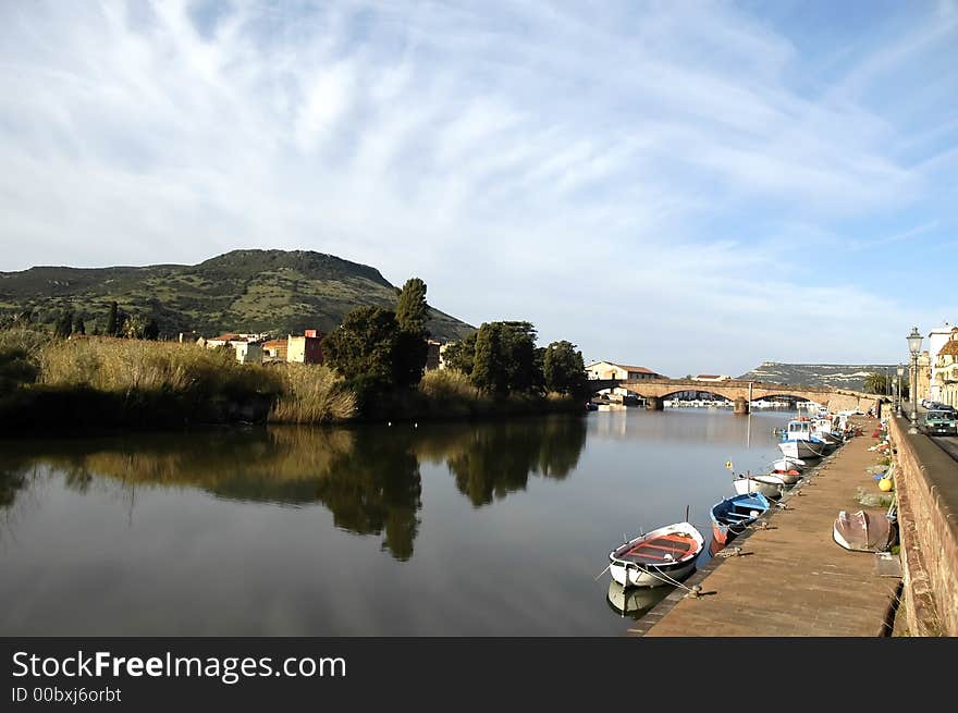 Landscape with bridge, boats and trees with reflections on water