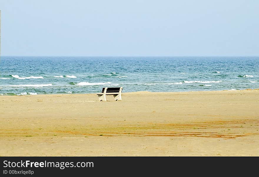 Solitary bench on an uncluttered beach, white caps on the waves. Solitary bench on an uncluttered beach, white caps on the waves.