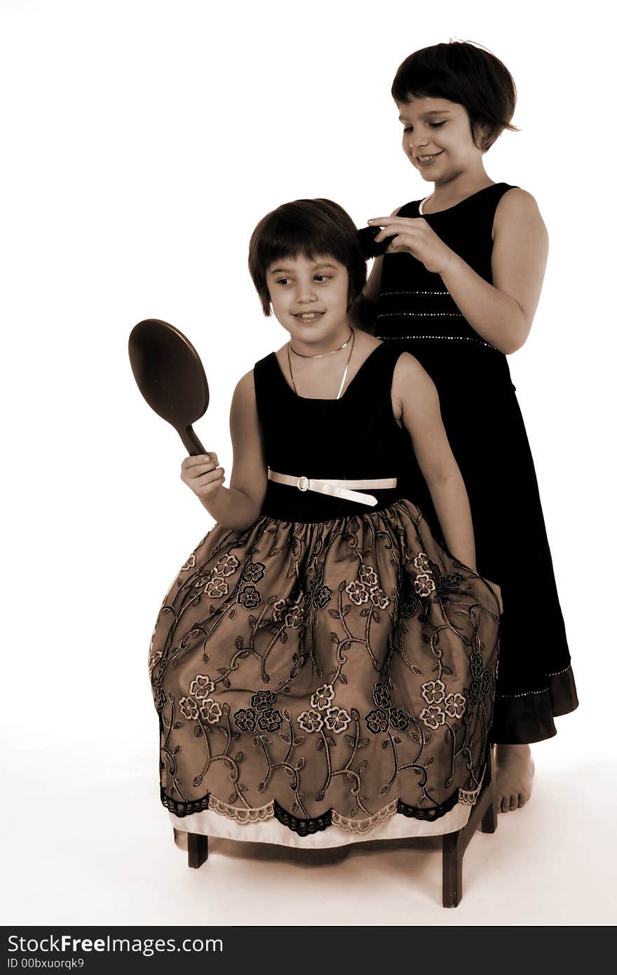 Adorable sisters helping each other get ready for a fancy affair.  Sepia toned, isolated on white. Adorable sisters helping each other get ready for a fancy affair.  Sepia toned, isolated on white.