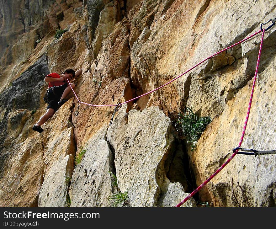 A young man is helping his teeth to delay a roap when he's climbing on a rock. A young man is helping his teeth to delay a roap when he's climbing on a rock