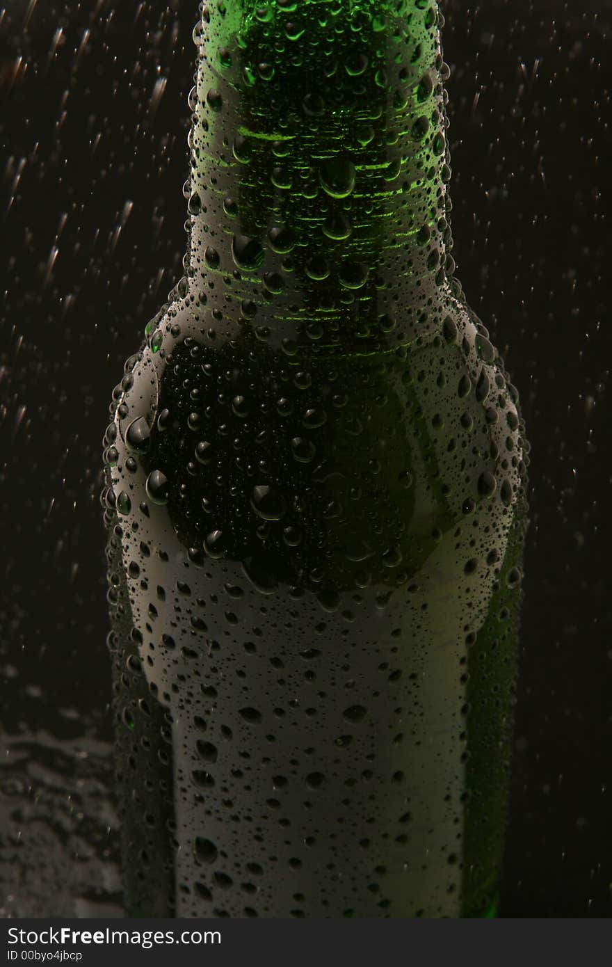 A cold bottle of beer being sprated with water. A cold bottle of beer being sprated with water