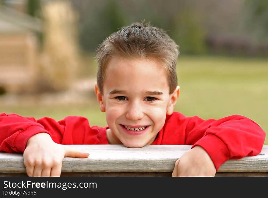 A Young Boy Smiling with chin on railing. A Young Boy Smiling with chin on railing