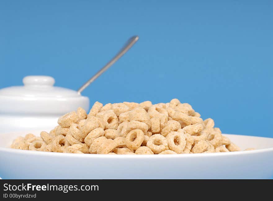 Oat Cereal In White Bowl With Sugar Bowl On Blue Background