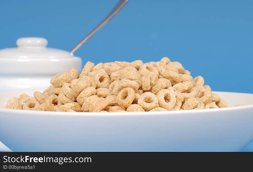 Bowl of oat cereal with sugar bowl on blue background