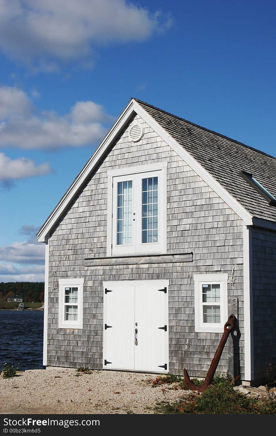 Building by a lake with an anchor leaning on the wall.