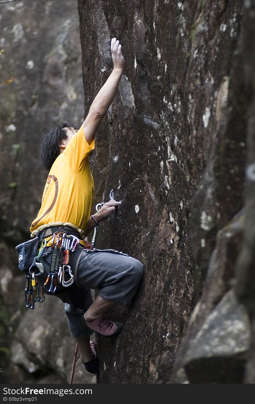 Asian rock-climber reacing for handhold. Asian rock-climber reacing for handhold