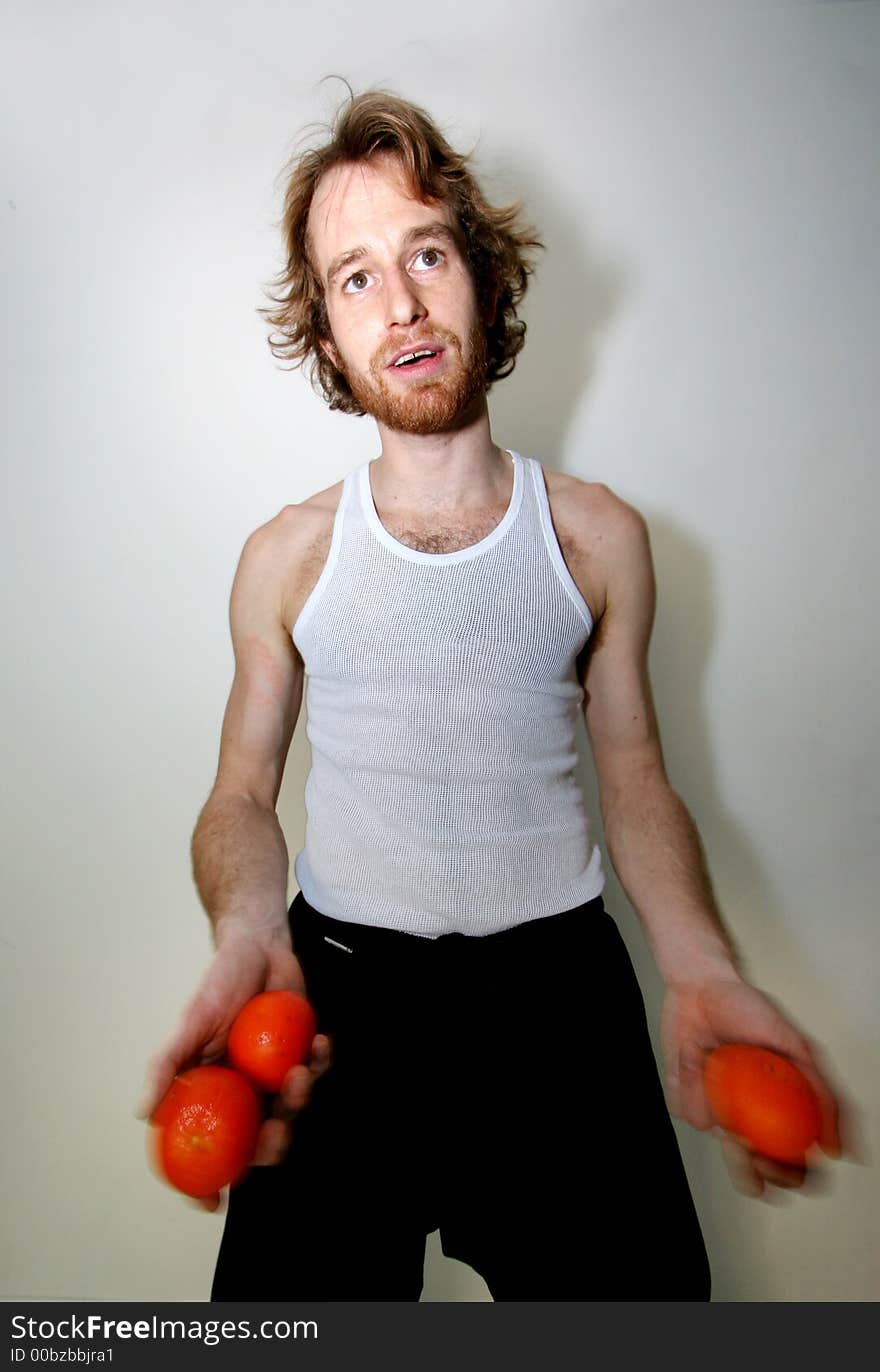 A young man juggling oranges. A young man juggling oranges