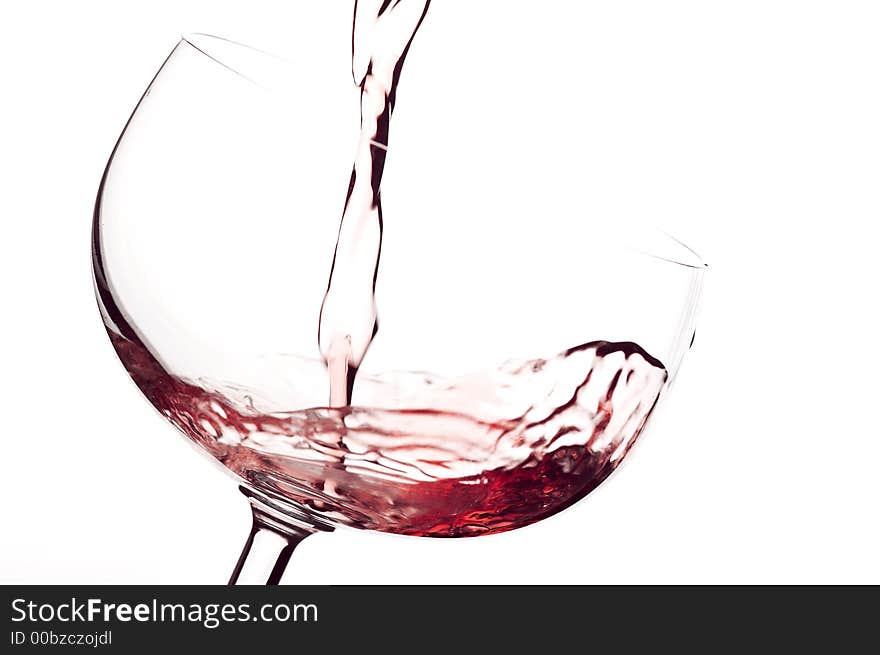 The red wine to flow in a glass. Isolated white. The red wine to flow in a glass. Isolated white.