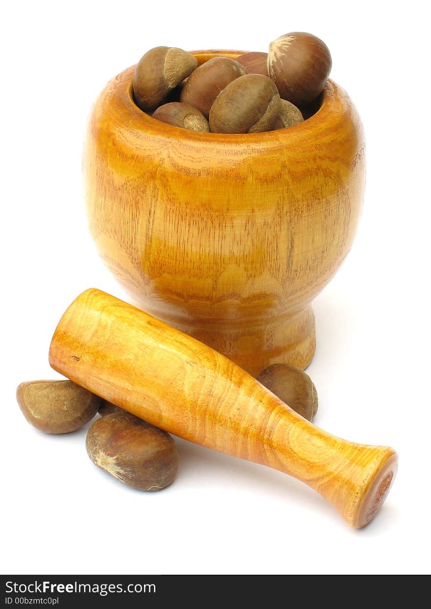 Wooden  mortar with pestle lying outside with chestnuts on white background. Wooden  mortar with pestle lying outside with chestnuts on white background