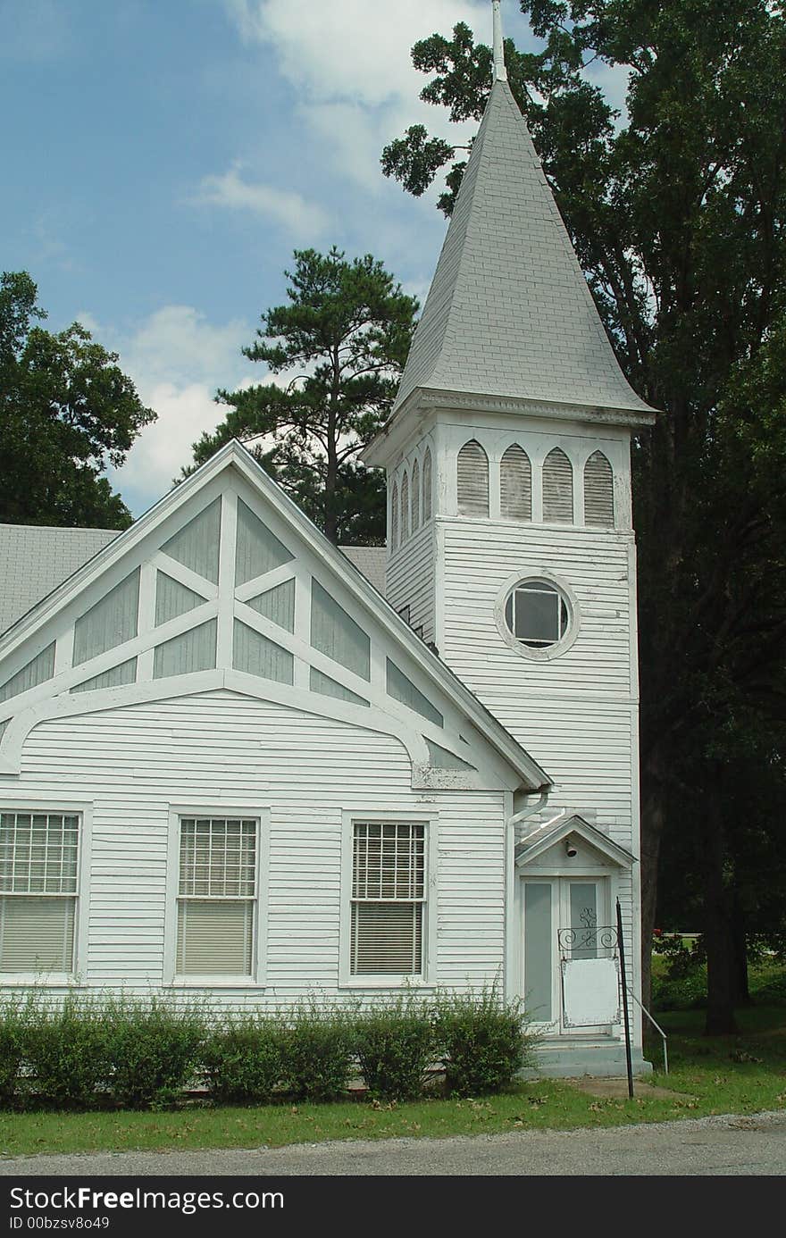 A simple, beautiful church with blue sky and trees.