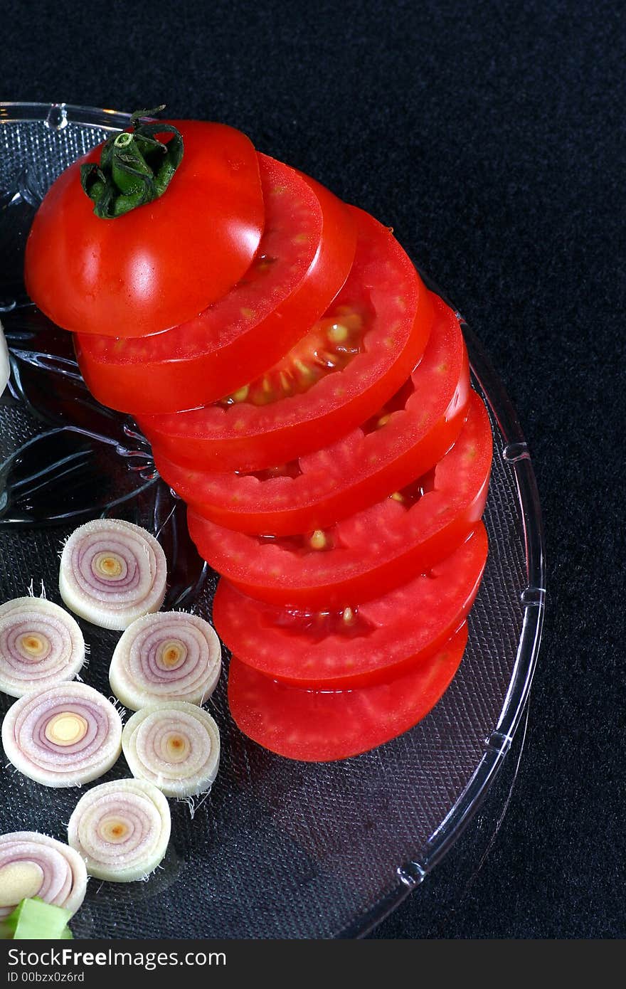 Tomato and lemongrass in pieces in glass dish on the black background