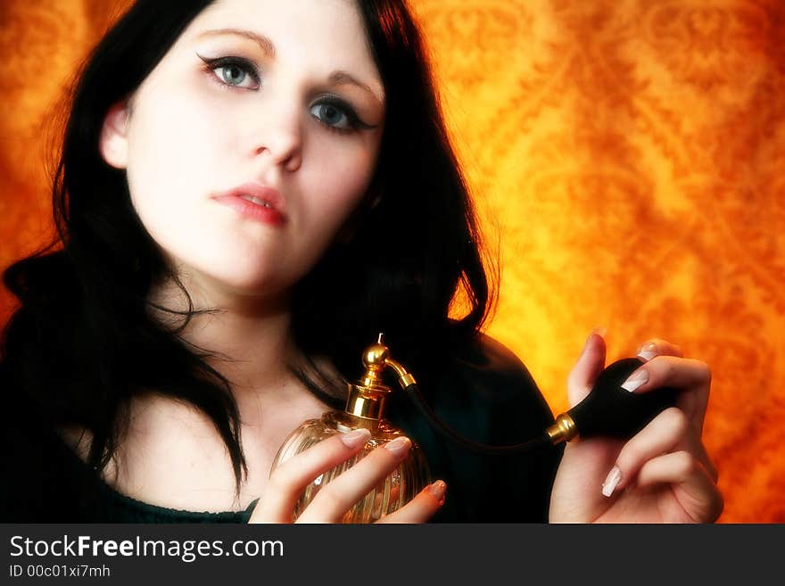 Beautiful young woman holding atomizer, perfume bottle.