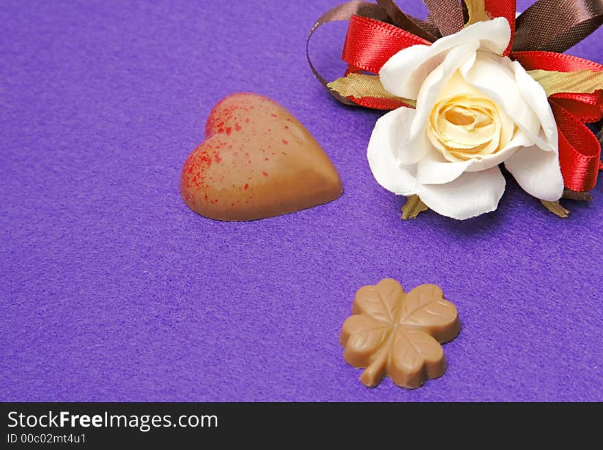 Still life with fancy Valentine chocolates and a rose over a violet background. Still life with fancy Valentine chocolates and a rose over a violet background.