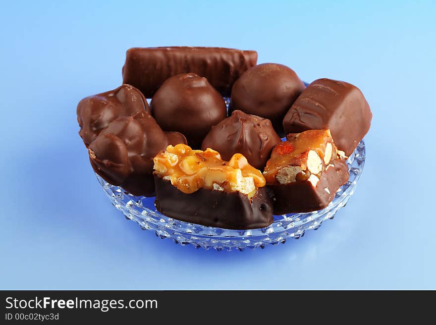 An assortment of chocolates arranged on a glass dish with a blue background. An assortment of chocolates arranged on a glass dish with a blue background.