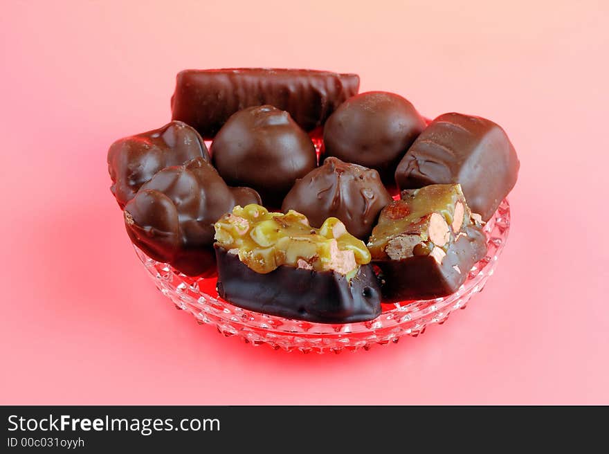 An assortment of chocolates arranged on a glass dish with a Peach colored background. An assortment of chocolates arranged on a glass dish with a Peach colored background.