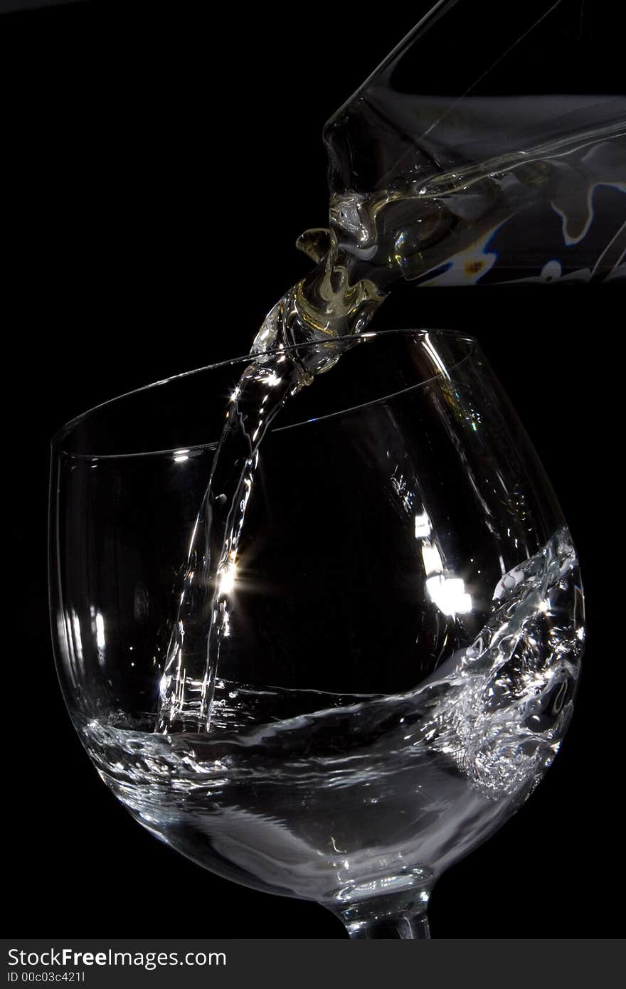 Water pouring from a decanter into a glass on black backrougnd. Water pouring from a decanter into a glass on black backrougnd