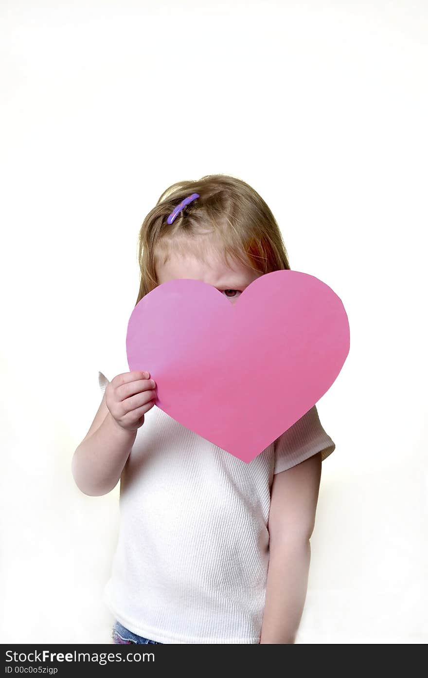 Little girl dressed in white holding a valentine heart. Little girl dressed in white holding a valentine heart