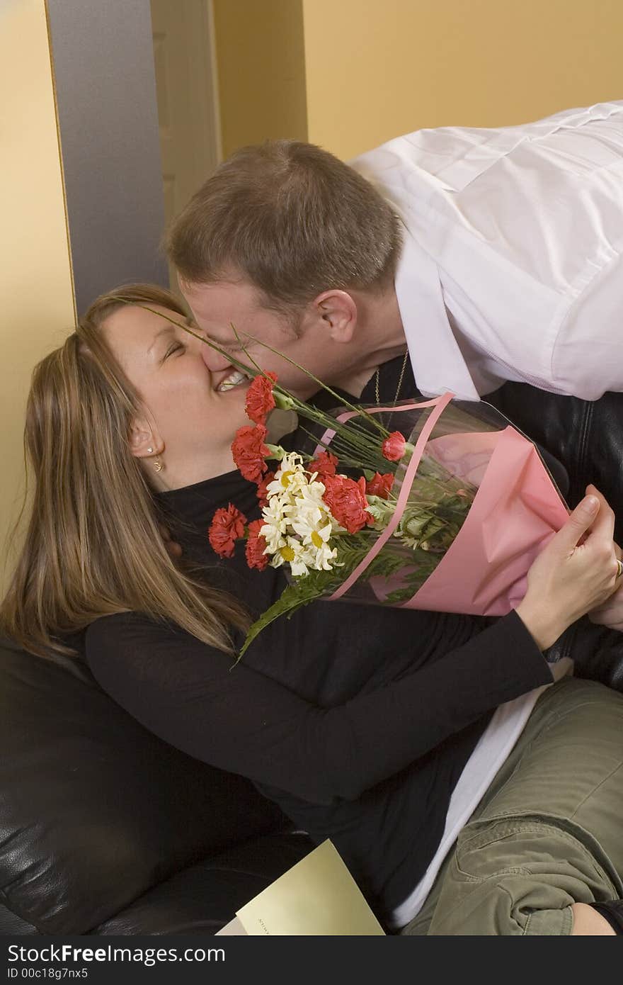 Man offering flower to woman sitting on couch. Man offering flower to woman sitting on couch