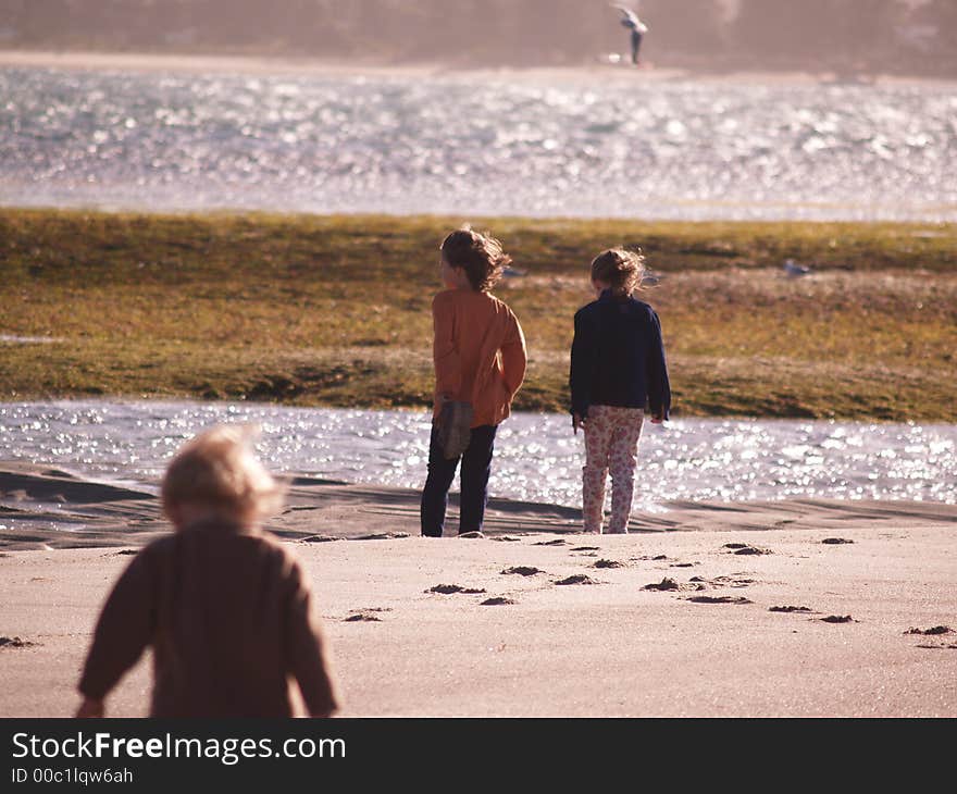 2 children standing at the seas edge, on a windy day. too cold to swim, but still a nice day for the beach. 2 children standing at the seas edge, on a windy day. too cold to swim, but still a nice day for the beach.