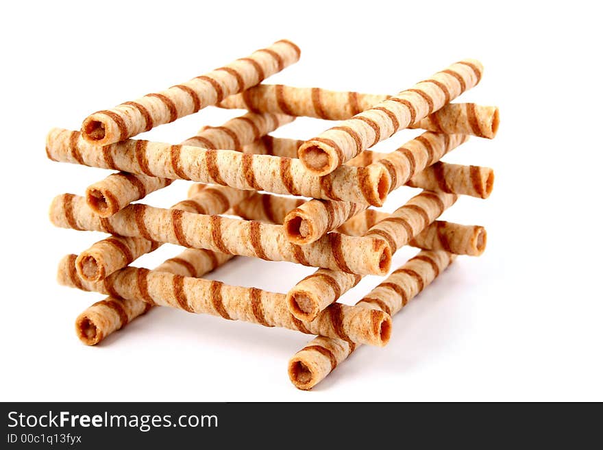 Heap of striped wafer tubules with the chocolate cream, isolated