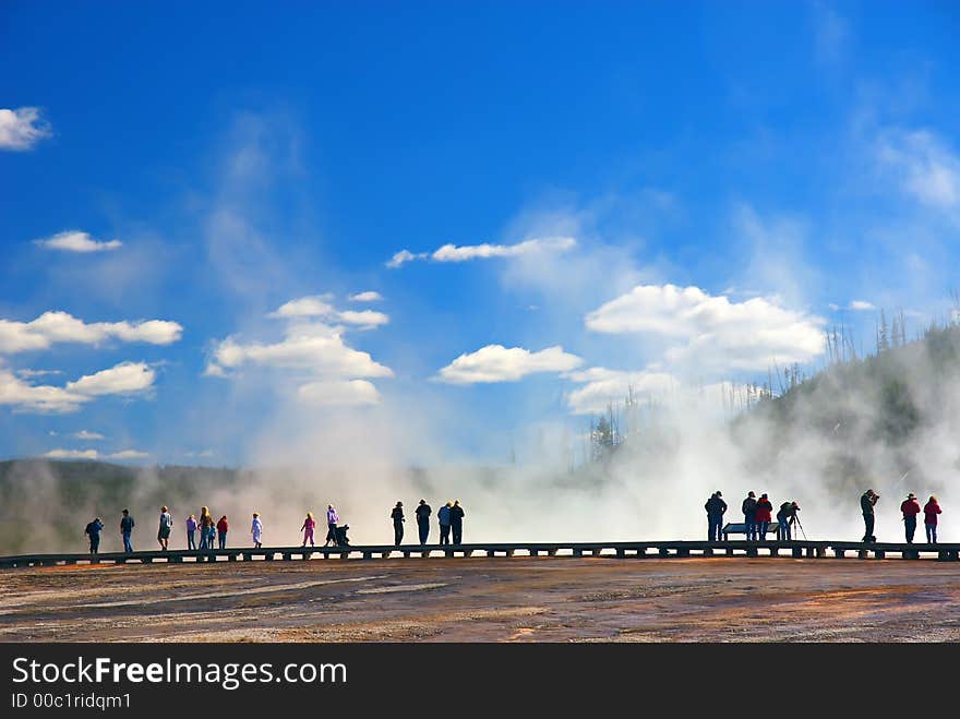 Tourist walking on edge of thermal pools in Yellowstone National Park. Tourist walking on edge of thermal pools in Yellowstone National Park