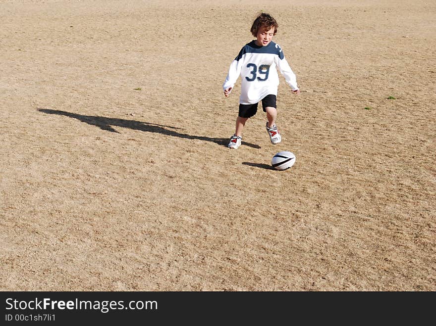 A boy chasing a football. A boy chasing a football